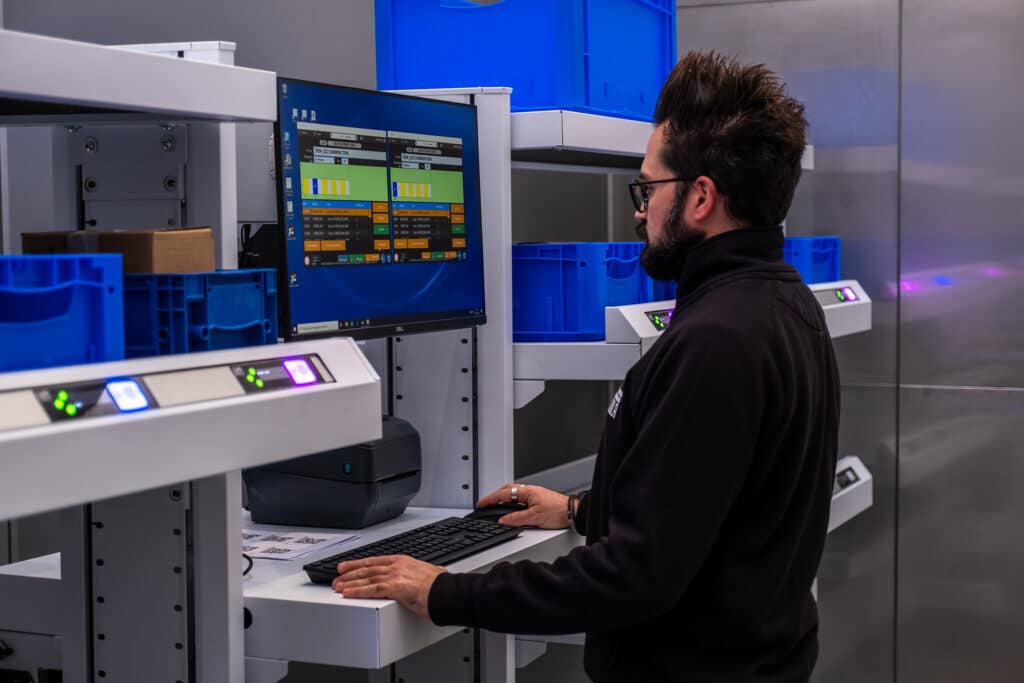 A man operating a picking station in a warehouse.