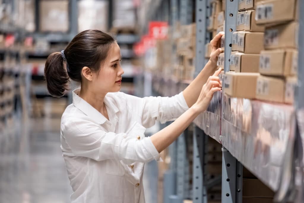 A woman browsing the warehouse inventory and reading box labels 