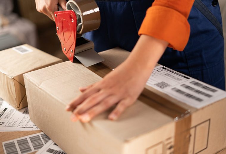 A warehouse employee sealing a box​