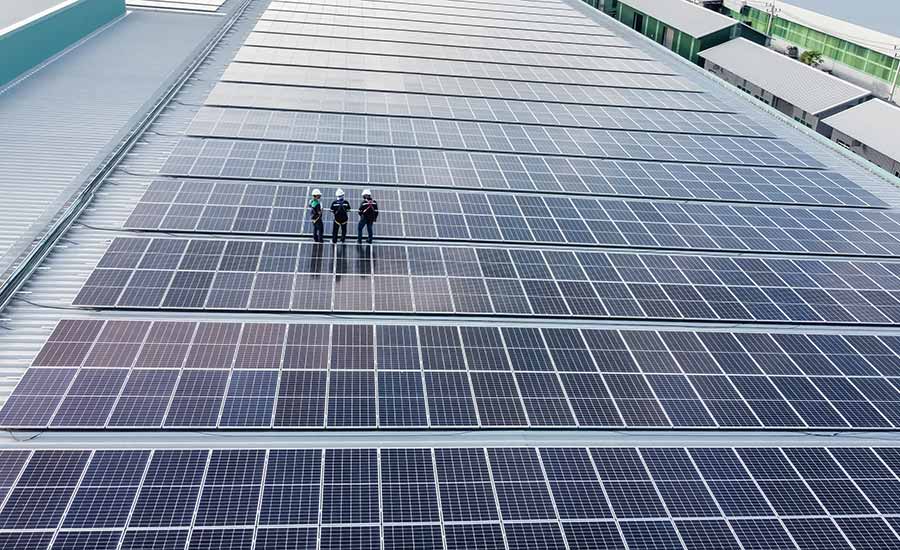 Three warehouse operators standing on solar panels