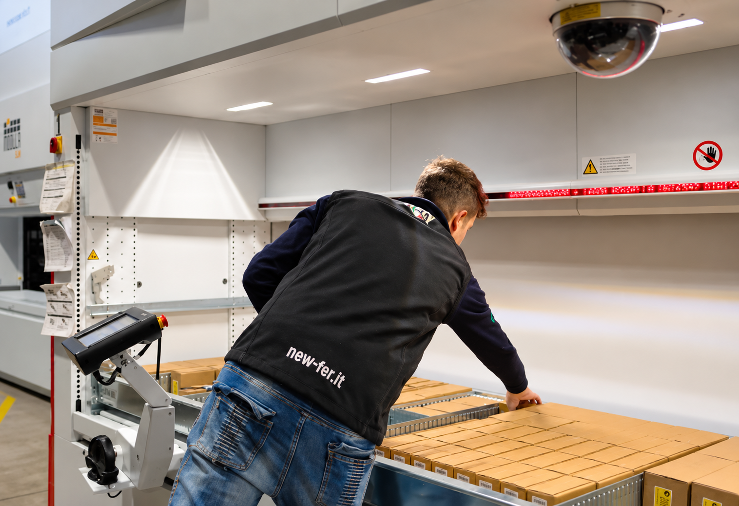 New Fer warehouse operator picking boxes from a Modula vertical lift module equipped with an LED picking indicator.